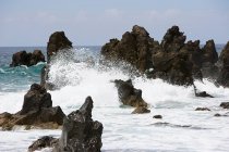 Formaciones rocosas de lava negra con olas rompientes - foto de stock