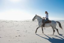 Женщина верхом на лошади на песке — стоковое фото