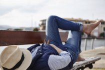 Mature woman lying on bench, hat covering face — Stock Photo