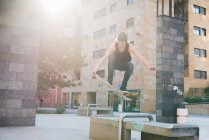 Jeune skateboarder homme sautant par-dessus le siège du hall urbain — Photo de stock