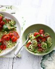 Tazones de tomate y pasta de hierbas en la mesa - foto de stock