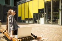 Junge unternehmerin entspannt sich auf bank vor büro, london, uk — Stockfoto