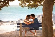 Casal beijando no banco do parque — Fotografia de Stock