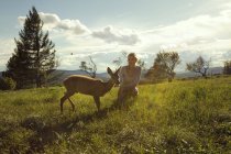 Young woman in field with fawn — Stock Photo