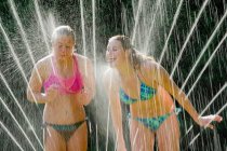 Teenage girls playing in sprinkler — Stock Photo
