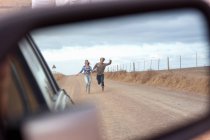 Couple running behind car — Stock Photo