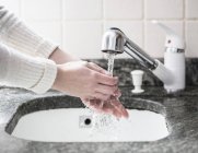 Plan recadré de jeune femme se lavant les mains dans l'évier — Photo de stock