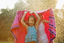 Meninas de pé sob toalha na chuva — Fotografia de Stock