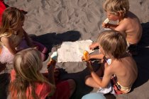Четверо друзів їдять морозиво на пляжі під високим кутом (Уельс, Велика Британія). — стокове фото
