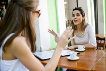 Женщины-подруги разговаривают за пределами кафе — стоковое фото
