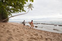 Due uomini che trasportano tavole da surf sulla spiaggia — Foto stock