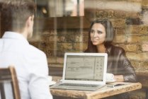 Молодой бизнесмен и женщина работают с ноутбуком и разговаривают в кафе — стоковое фото
