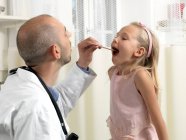 Médico examinando chica en clínica - foto de stock