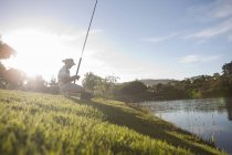 Зрілий чоловік риболовля на мирному березі річки — стокове фото