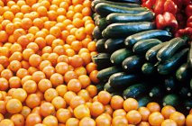 Pimientos, calabacines y naranjas maduros en el mercado - foto de stock