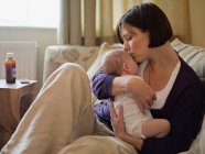 Una madre besando a su nuevo bebé - foto de stock