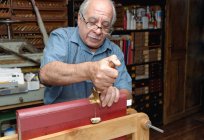Hombre mayor aplicando la hoja de oro a la columna vertebral del libro en el taller tradicional de encuadernación - foto de stock