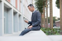 Uomo d'affari in pausa pranzo messaggiando su smartphone — Foto stock