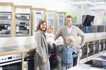 Portrait of family with two children browsing hobs in electronics store — Stock Photo