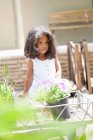 Девушка сидит на тележке в цветочном питомнике — стоковое фото