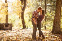 Young couple kissing in autumn forest — Stock Photo