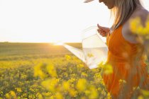 Cropped view of mid adult woman watering canola with transparent watering can — Stock Photo