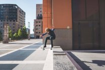 Joven skateboarder skateboarding hasta el paso urbano - foto de stock