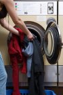Tiro recortado de la mujer cargando lavadora - foto de stock