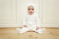 Baby boy wearing bear babygro sitting on floor — Stock Photo