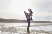 Homem adulto médio levantando a filha na praia, Bloemendaal aan Zee, Holanda — Fotografia de Stock