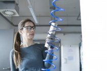 Женщина в мастерской в защитных очках, держит пульт управления — стоковое фото