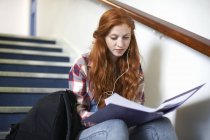 Young female college student sitting on stairway reading file — Stock Photo