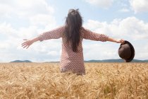 Femme adulte moyenne debout dans le champ de blé avec les bras écartés — Photo de stock