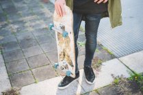 Waist down view of young male urban skateboarder standing on sidewalk — Stock Photo