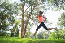 Giovane donna che corre attraverso il parco — Foto stock