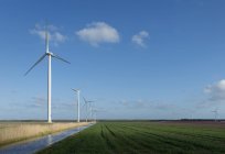 Turbine eoliche sul campo sotto cielo nuvoloso blu — Foto stock