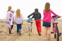 Девочки, гуляющие по песку на пляже — стоковое фото
