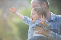 Vista laterale del bambino tenuto in braccio dal padre, indicando eccitatamente — Foto stock