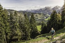 Woman hiking up Zinken mountain with walking poles, Oberjoch, Bavaria, Germany — Stock Photo