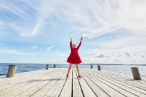 Young girl on wooden pier, jumping to reach bubbles — Stock Photo