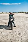 Homem adulto médio sentado na motocicleta na planície árida, Cagliari, Sardenha, Itália — Fotografia de Stock