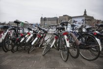 Ряди припаркованих велосипедів на вулиці з хмарним небом — стокове фото