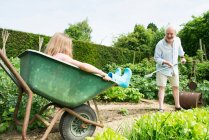 Mädchen im Schubkarren, Großvater bei der Gartenarbeit — Stockfoto