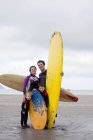 Портрет семьи с двумя мальчиками с досками для серфинга на пляже — стоковое фото