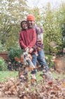 Padre e hijo usando el golpe de la hoja para despejar las hojas de otoño, riendo - foto de stock