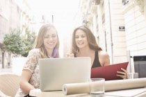 Two young female friends looking at laptop at sidewalk cafe, Valencia, Spain — Stock Photo