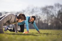 Jovem e mulher fazendo empurrar para cima o treinamento no campo de jogo — Fotografia de Stock