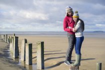 Casal jovem em pé sobre groynes, Brean Sands, Somerset, Inglaterra — Fotografia de Stock