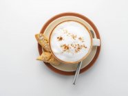 Vue du dessus du cappuccino en tasse sur soucoupe avec cuillère en argent et biscuits — Photo de stock