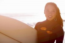 Jeune femme en combinaison avec planche de surf — Photo de stock